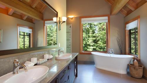 uma casa de banho com 2 lavatórios, uma banheira e 2 janelas em Kadenwood 2972 - Mountain Chalet, w/ Hot Tub, Pool Table, Fireplace - Whistler Platinum em Whistler