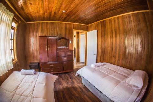 1 dormitorio con 2 camas y pared de madera en Edelweishaus, en Chontabamba