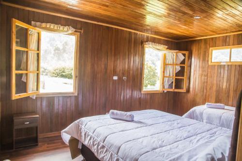 1 dormitorio con 2 camas y 2 ventanas en Edelweishaus, en Chontabamba