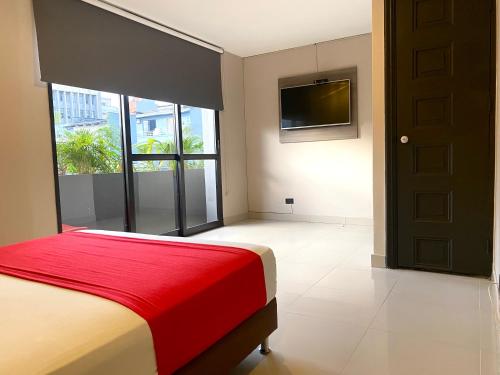 Hotel Latino Medellín في ميديلين: غرفة نوم بسرير وبطانية حمراء وتلفزيون