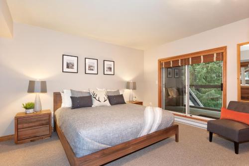 ein Schlafzimmer mit einem Bett, einem Stuhl und einem Fenster in der Unterkunft Stoneridge 12 in Whistler