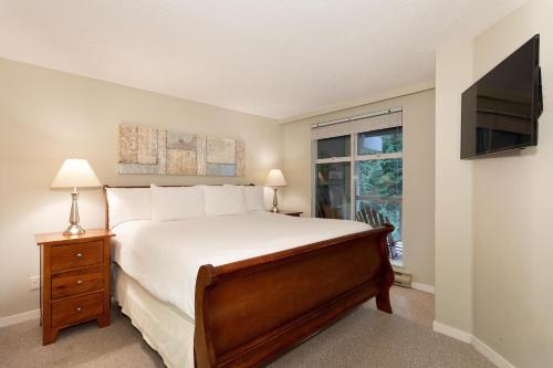 a bedroom with a bed and a tv and a window at Woodrun Lodge 514 - Modern 1Bed + Den Condo with Pool, Hot Tub, Gym - Whistler Platinum in Whistler