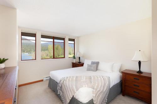 a white bedroom with a bed and two windows at Lakeside Landing - Lake & Golf Course Views from Private Balcony - Whistler Platinum in Whistler