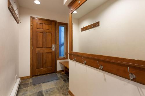 a hallway with a wooden door and a bench at Blackcomb Greens 06 - Large Townhome, Golf Course Views, Shared Hot Tub - Whistler Platinum in Whistler
