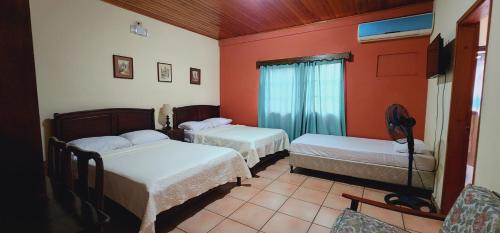 2 camas en una habitación con paredes rojas en Hotel Alsacia, en Tegucigalpa