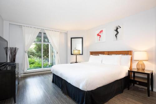 Un dormitorio con una gran cama blanca y una ventana en Woodrun Lodge 107 - Condo with Heated Pool, Hot Tub, Gym, Parking - Whistler Platinum, en Whistler