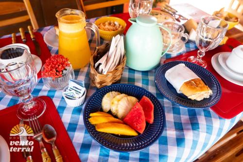 a table with plates of fruit on a blue and white checked table cloth at Pousada Vento Terral in Pipa