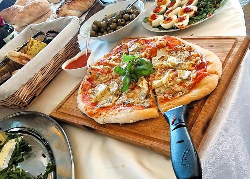 a pizza on a cutting board on a table with a knife at PiranArt Boutique Hotel & More in Piran