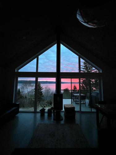 a room with a large window looking out at a sunset at Magical Loft : Breathtaking View & Cozy Fireplace in Saguenay
