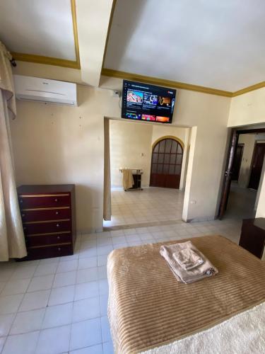 1 dormitorio con 1 cama y TV en la pared en Departamento en zona céntrica de Yacuiba en Yacuíba
