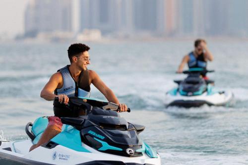 two men riding on jet skis in the water at The St. Regis Doha in Doha