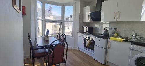 une cuisine avec une table et des chaises et une cuisine avec une fenêtre dans l'établissement Comfy 2 bedroom Apt in central location, Newly Refurbished, à Plymouth