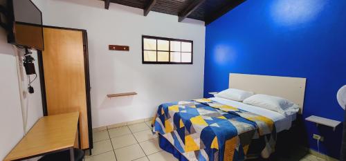 Schlafzimmer mit einem Bett mit blauer Wand in der Unterkunft Hotel Ghiza in Tegucigalpa