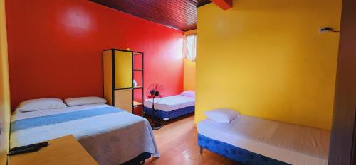 a bedroom with two beds and red and yellow walls at Hotel Ghiza in Tegucigalpa