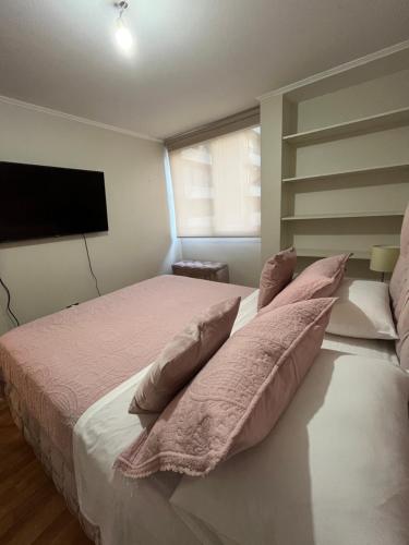 a bedroom with a bed with pillows and a flat screen tv at Amoblados Chile Rent San Diego in Santiago