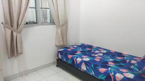 a bedroom with a bed with a floral bedspread and a window at RIZQI HOMESTAY PRIMA PRESINT 11 PUTRAJAYA in Putrajaya