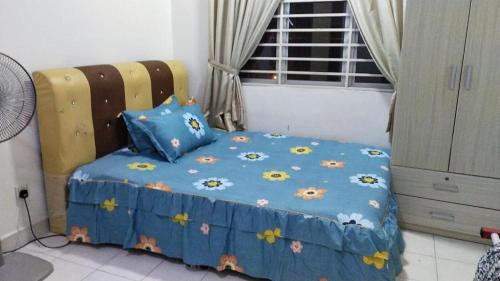 a bed with a blue comforter with flowers on it at RIZQI HOMESTAY PRIMA PRESINT 11 PUTRAJAYA in Putrajaya