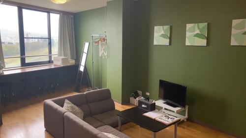 a living room with a couch and a tv at Riverside TABI-NE in Kanazawa