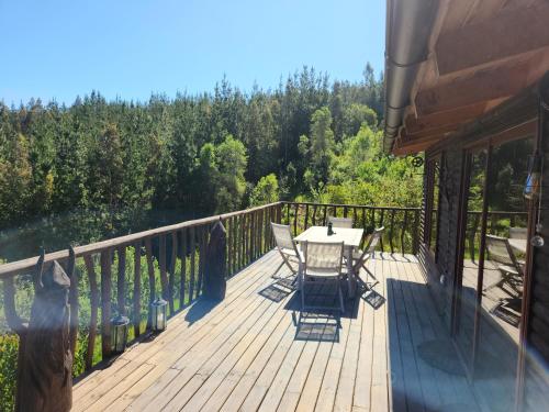 una terraza de madera con mesa y sillas. en ArboLodge, en Vichuquén