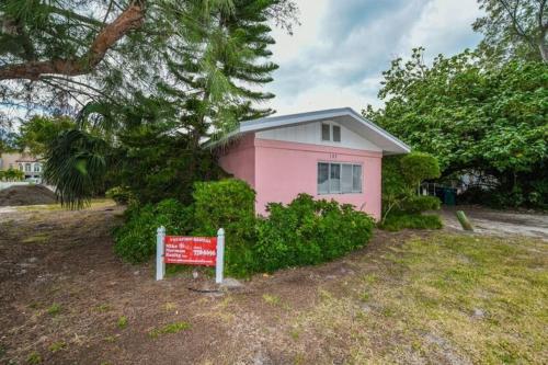 una casa rosa con un cartel delante en The Seashell, Private Home #54561 Home, en Holmes Beach