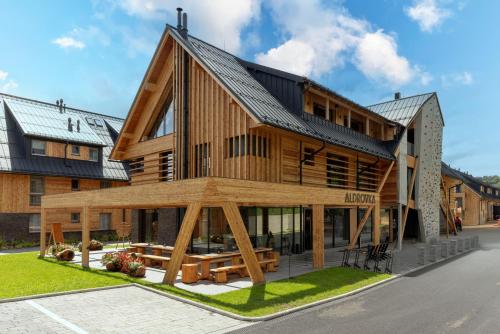 a large wooden house with a gambrel roof at Aldrov Resort in Vítkovice