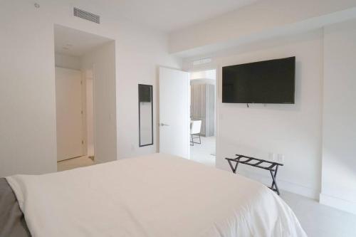 a white bedroom with a bed and a flat screen tv at Brand New Apartment in Brickell with parking in Miami