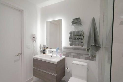 a white bathroom with a sink and a mirror at Brand New Apartment in Brickell with parking in Miami