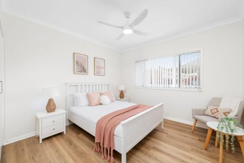 biała sypialnia z łóżkiem i kanapą w obiekcie 2A Rigney Street Shoal Bay w mieście Shoal Bay
