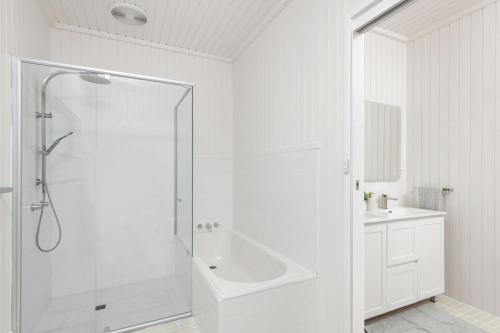 biała łazienka z prysznicem i umywalką w obiekcie 2A Rigney Street Shoal Bay w mieście Shoal Bay