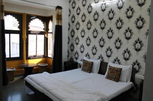 a bedroom with a white bed with a wall at Hill Paradise Home Stay in Udaipur
