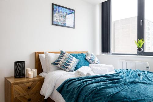 a bedroom with a bed with blue blankets and pillows at Luxurious Stylish Apartment in Old Trafford in Manchester
