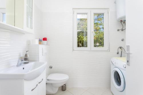 La salle de bains blanche est pourvue d'un lavabo et d'une fenêtre. dans l'établissement Apartments by the sea Seget Vranjica, Trogir - 1038, à Seget Vranjica