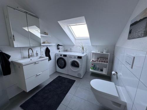 a white bathroom with a washing machine and a sink at Cozy apartment in the Sauerland in Brilon