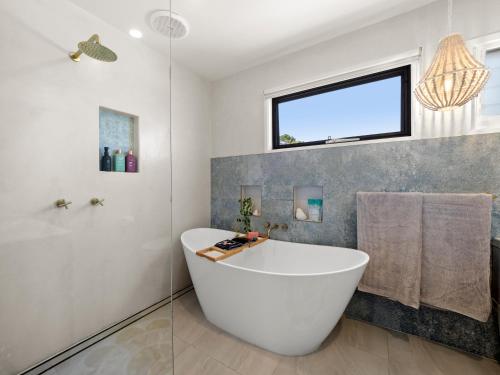 a bathroom with a large tub and a window at Lazy Days Penthouse - Opposite Shaws Bay - 180 Waterfront Views in East Ballina