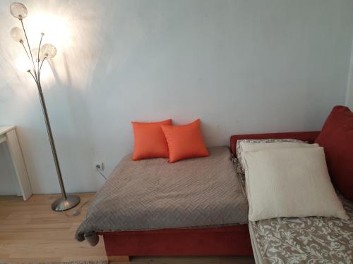 a bedroom with a bed with orange pillows and a lamp at LjubljanaArt Apartment in Ljubljana
