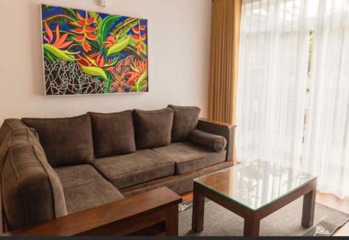 sala de estar con sofá, mesa y pintura en Avenue Nuwara Eliya en Nuwara Eliya