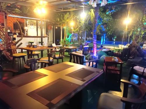a restaurant with tables and chairs at night at OASIS Phuket Airport in Ban Bo Sai Klang