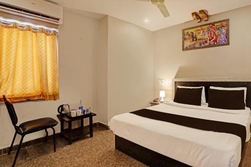 een hotelkamer met een bed en een stoel bij Super Capital O Hotel Vaishnavi in Secunderābād