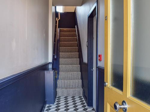 a hallway with stairs and a yellow door at Apartment One - Uk45352 in Southport
