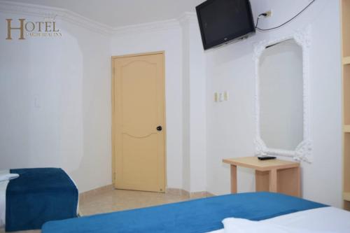 um quarto com uma cama e uma televisão na parede em Hotel Caribe Real Inn em Santa Marta