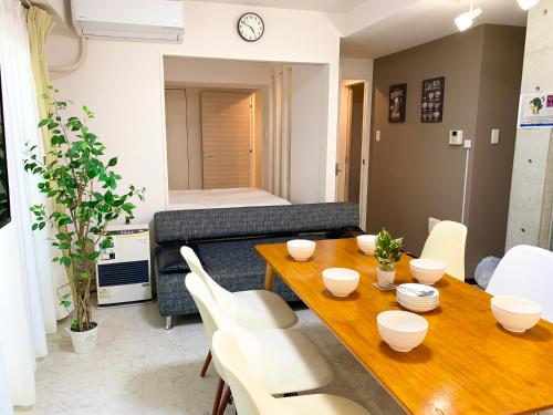 a living room with a wooden table and white chairs at O2 capsule house OTARU in Otaru