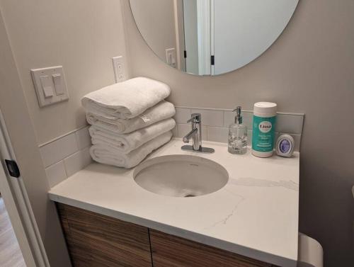 a bathroom with a sink with a mirror and towels at Comfy 2BR condo in Seton, Southeast Calgary in Calgary