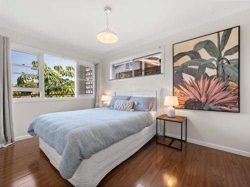 a white bedroom with a bed and two windows at Two Apartments Stray Leaves & The Jungle Room - 150m to Shaws Bay in East Ballina