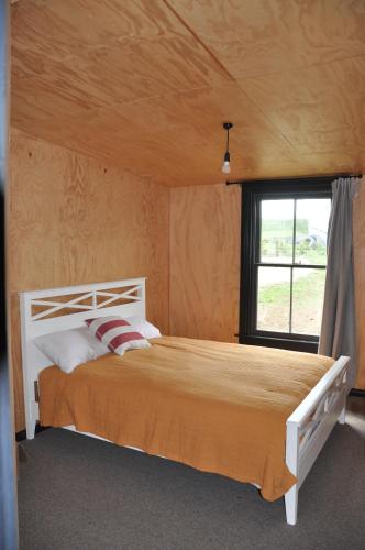 um quarto com uma cama num quarto com uma janela em Renagour Cottage - Farmstay with Hot Tub! em Whanganui