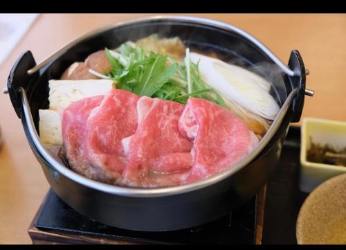 a pan filled with meat and vegetables on a table at O2 capsule house OTARU in Otaru