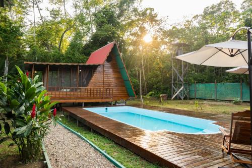 a swimming pool in front of a house with an umbrella at Aroldo Amazon Lodge in Puerto Maldonado