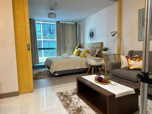 ein Schlafzimmer mit einem Bett, einem Sofa und einem Tisch in der Unterkunft A Residence with a Mall and a Nightlife @Uptown, BGC in Manila