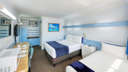 a hotel room with two beds and a desk at Tumut Farrington motel in Tumut