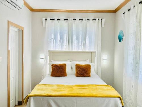 een slaapkamer met een wit bed met 2 kussens bij The Shelton Tower 2 in Montego Bay