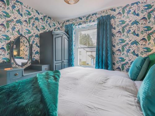 a bedroom with a large bed with blue curtains at Pooley Bridge Apartment - Uk44955 in Pooley Bridge